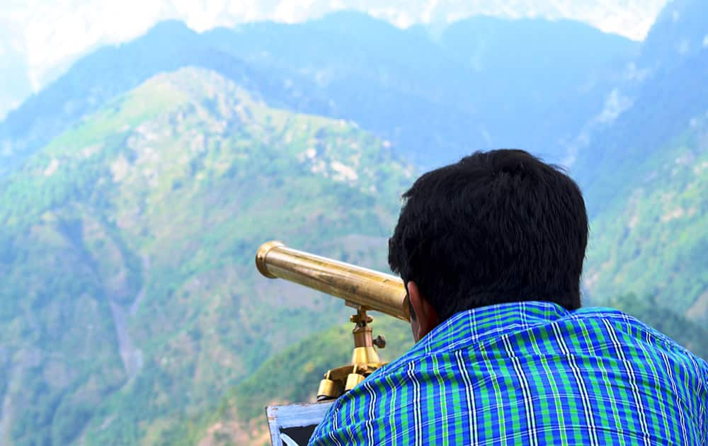 A tourist taking a closer look of the Dhauladhar at Naddi View Point.