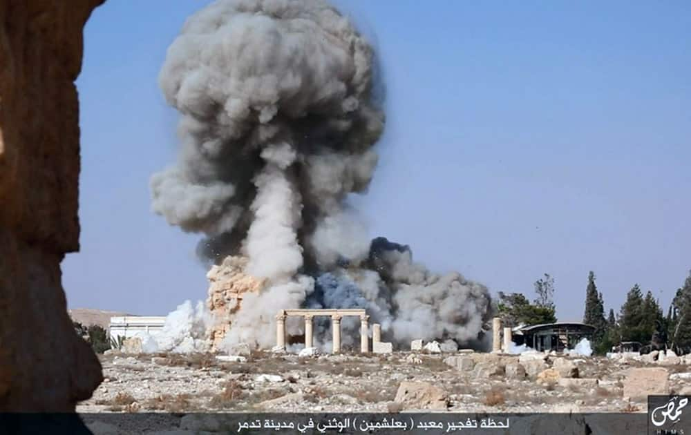 This undated photo released on a social media site used by Islamic State militants, which has been verified and is consistent with other AP reporting, shows smoke from the detonation of the 2,000-year-old temple of Baalshamin in Syria's ancient caravan city of Palmyra. A resident of the city said the temple was destroyed on Sunday, a month after the group's militants booby-trapped it with explosives. Arabic at bottom reads, 'The moment of detonation of the pagan Baalshamin temple in the city of Palmyra.'