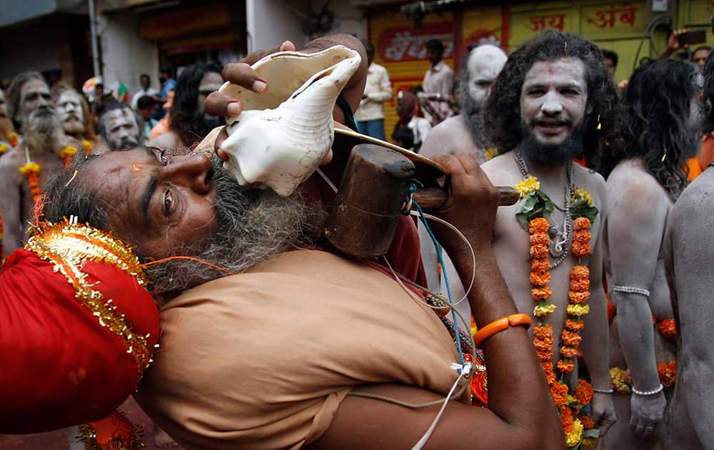 A Naga sadhu, or naked Hindu holy man, blows into a conch shell as he participates in a procession during Kumbh Mela, or Pitcher festival, at Trimbakeshwar in Nasik, India.