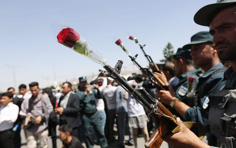 Afghan civil society activists place flowers in security forces rifles during a peace message parade to appreciate the hard work of Afghan security forces and say no to terrorist attacks in Kabul, Afghanistan.