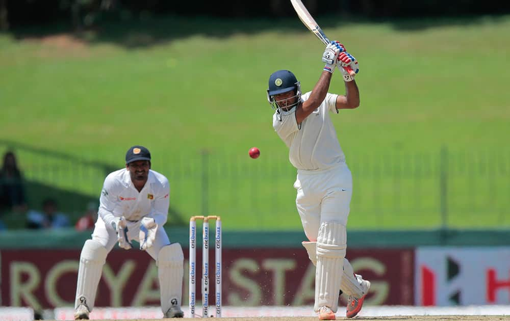 Cheteswar Pujara plays a shot as Sri Lankan wicket keeper Kusal Janith Perera watches on the second day of their third test cricket match in Colombo.