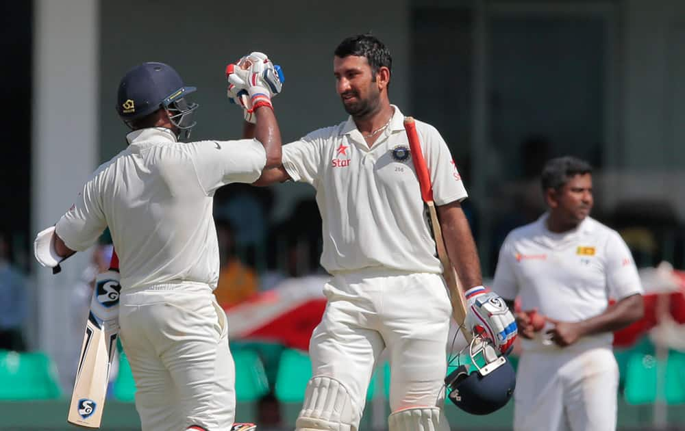 Cheteshwar Pujara, century celebrates scoring a hundred runs with teammate Amit Mishra, back to camera on the second day of their third test cricket match against Sri Lanka in Colombo.