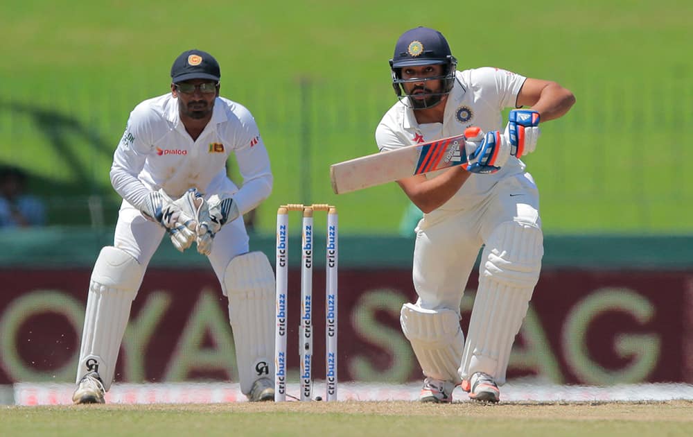 Rohit Sharma plays a shot as Sri Lankan wicket keeper Kusal Janith Perera watches on the second day of their third test cricket match in Colombo.