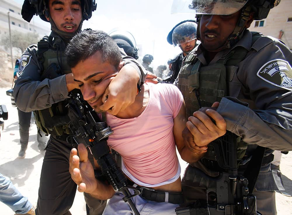 Israeli border police detain a Palestinian during a protest against the Israeli separation barrier, in Beit Jala, West Bank.