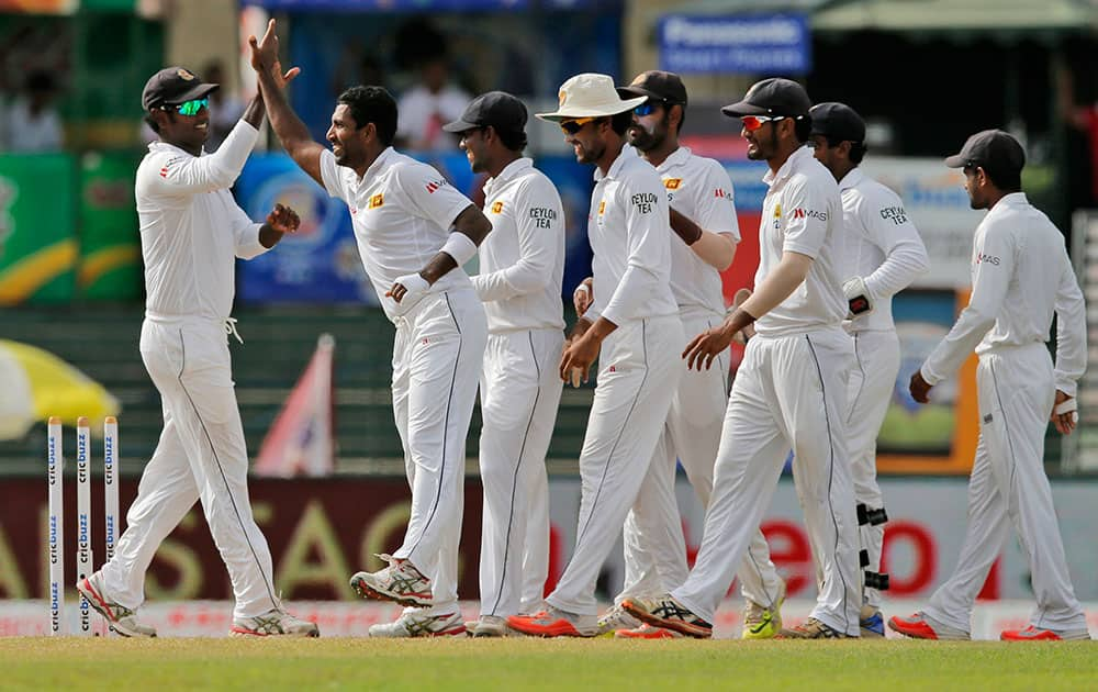 Sri Lanka's Dhammika Prasad, second left, celebrates with teammates the dismissal of India's Cheteshwar Pujara on the third day of their third test cricket match between them in Colombo, Sri Lanka.