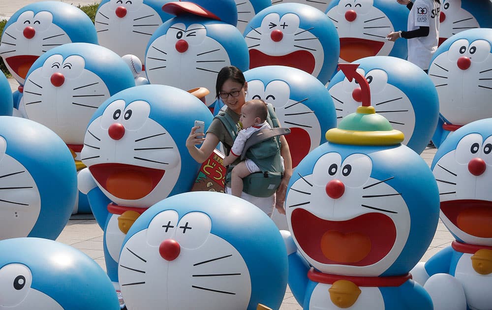 A woman poses with her baby among dolls featuring the Japanese animation character Doraemon during an exhibition at a department store in Seoul, South Korea.