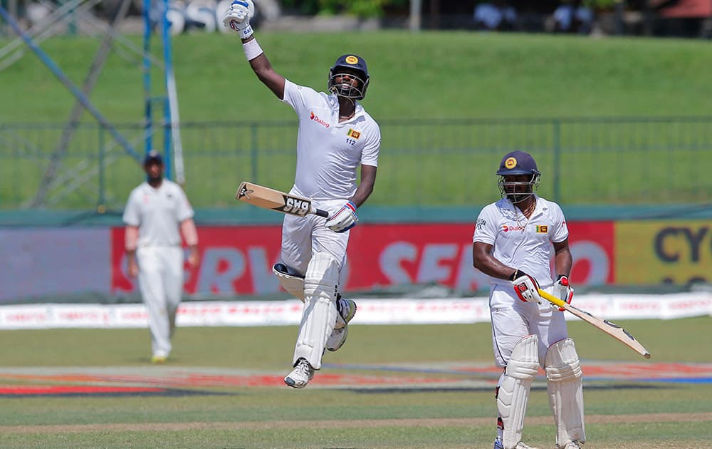 Angelo Mathews jumps as he celebrates scoring a hundred as non striker Kusal Janith Perera watches on the final day of their third test cricket match in Colombo, Sri Lanka.