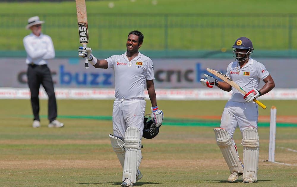 Sri Lanka's Angelo Mathews celebrates scoring a hundred as non striker Kusal Janith Perera watches on the final day of their third test cricket match in Colombo, Sri Lanka.