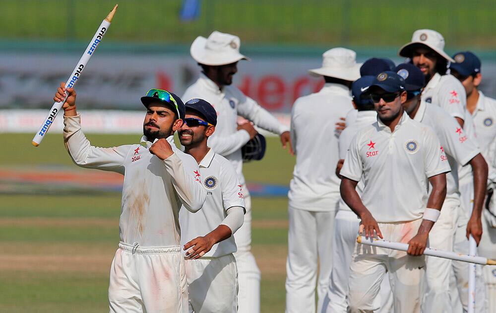 Virat Kohli holds a stump as he leads his team off the pitch after defeating Sri Lanka in their third test cricket match in Colombo, Sri Lanka. India won by 117 runs.