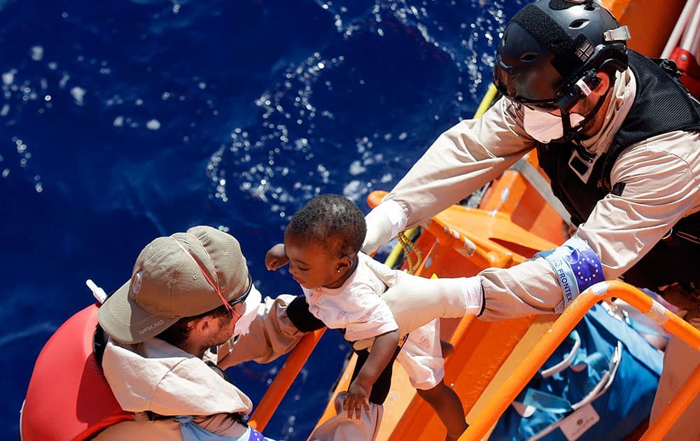 A baby is helped to board on the Norwegian Siem Pilot ship during a migrant search and rescue mission off the Libyan Coasts.