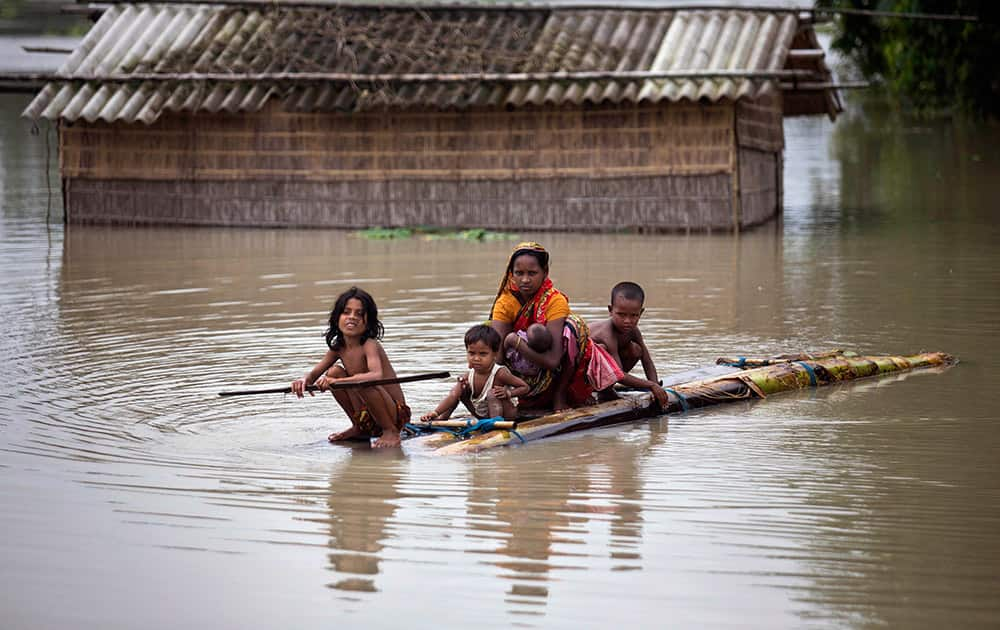 A family uses a makeshift banana raft to cross floodwaters as they try to reach safer areas at Kholabuya village, 65 kilometers (40 miles) from Guwahati.