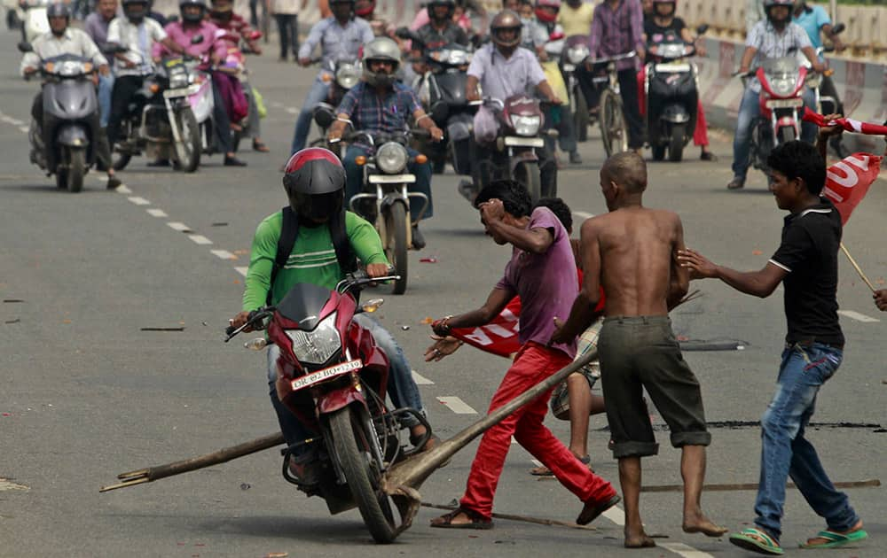 Activists of a trade union group try to stop a motorcyclist to keep vehicles off the road during a daylong nationwide strike in Bhubaneswar.