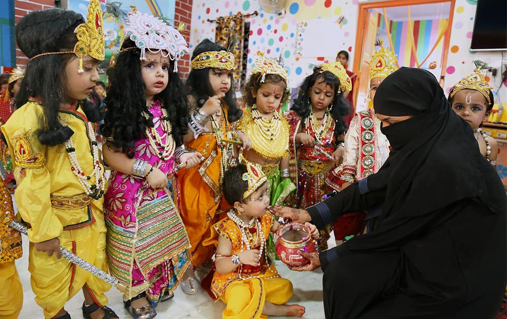 A muslim woman feeding makhan to her children dressed as Lord Krishna at a school during Krishna Janmashtami celebrations at Beawar in Rajasthan.