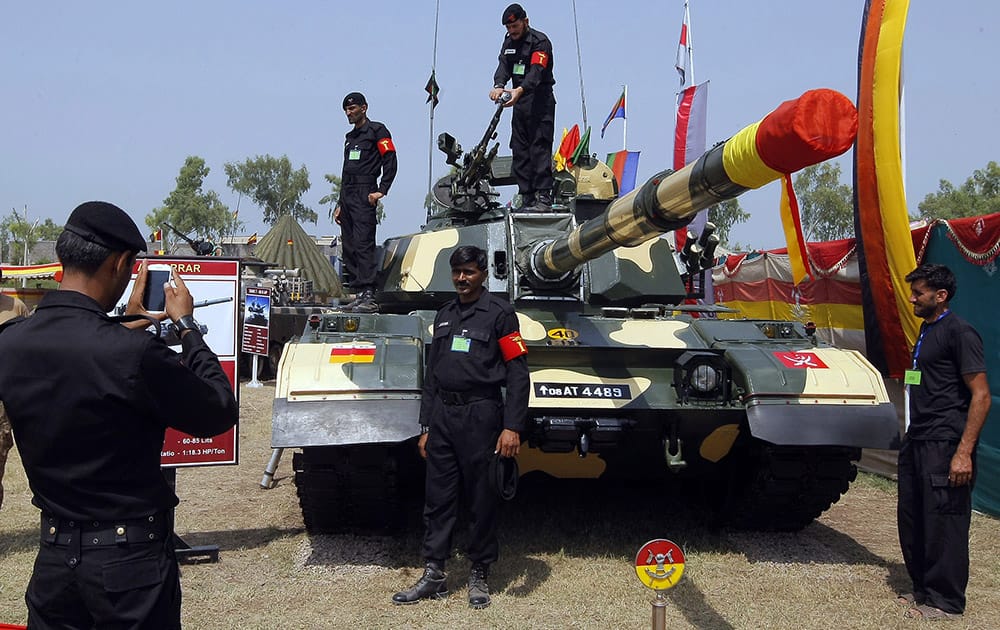 A soldier uses a mobile phone to take a photograph of his colleague in front of a Pakistan-made Al-Zarrar tank, on display for the forthcoming Pakistan Defense Day ceremony in Peshawar.