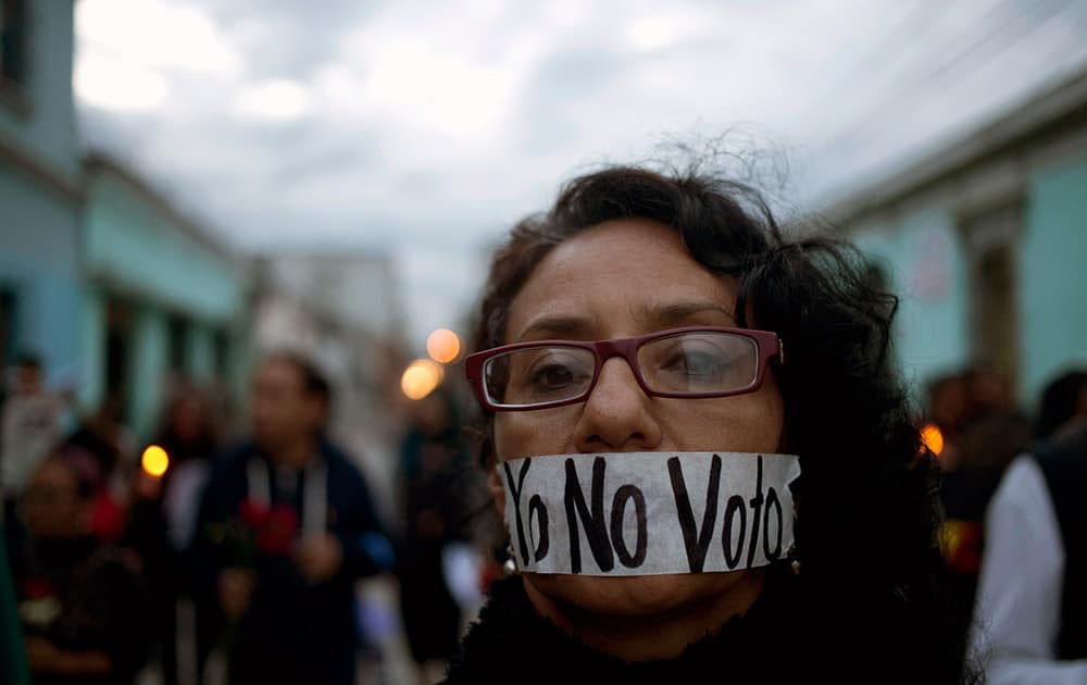 A demonstrator covers her mouth with tape carrying the message Spanish: 