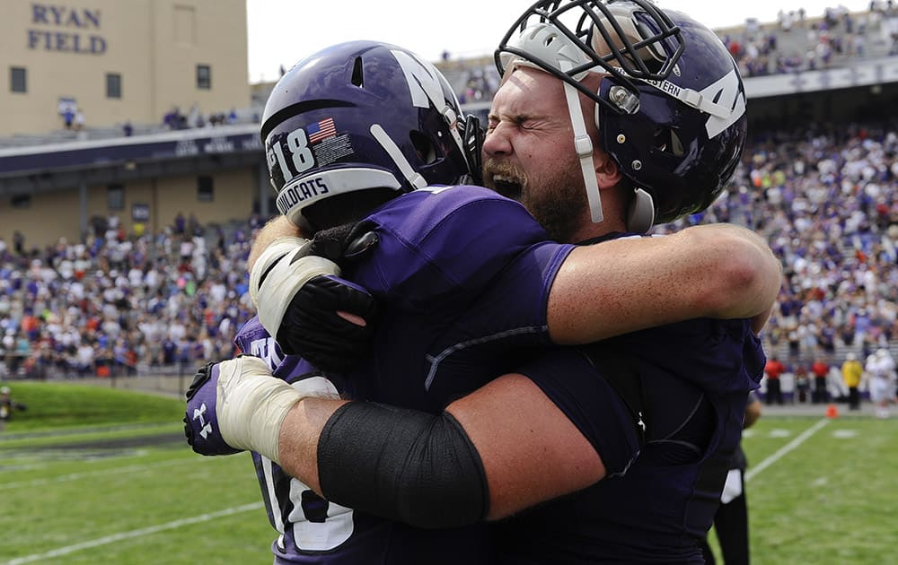 Northwestern quarterback Clayton Thorson (18), left, and offensive lineman Eric Olson (76) hug after beating Stanford 16-6 in an NCAA college football game in Evanston, Ill.