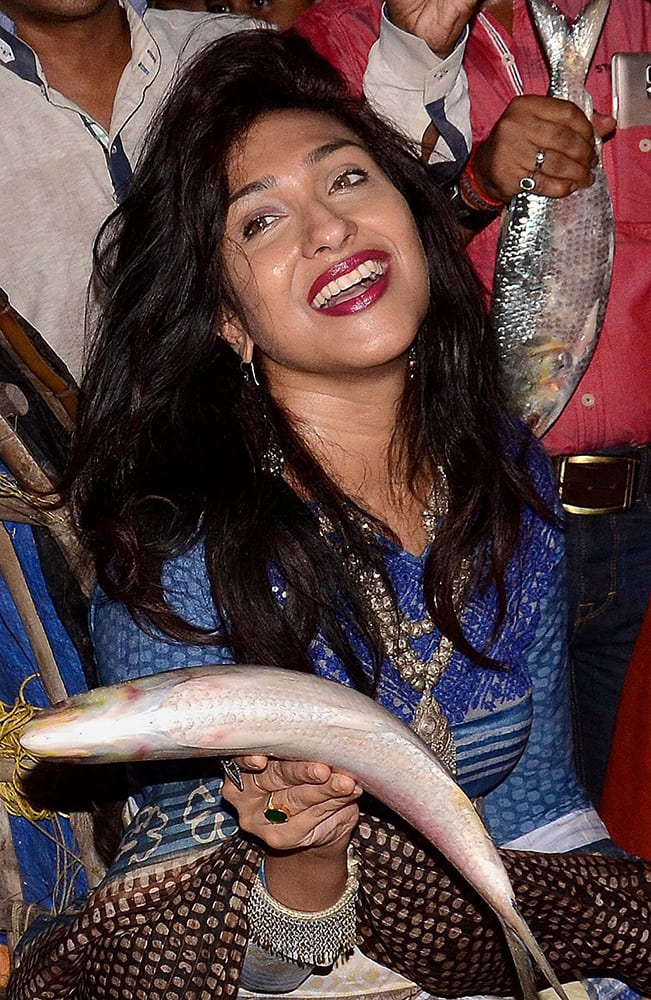 Actress Rituparna Sengupta shows an Elisha fish while sitting on a fishing boat during the inauguration of Eilsha Fish Festival in Kolkata.