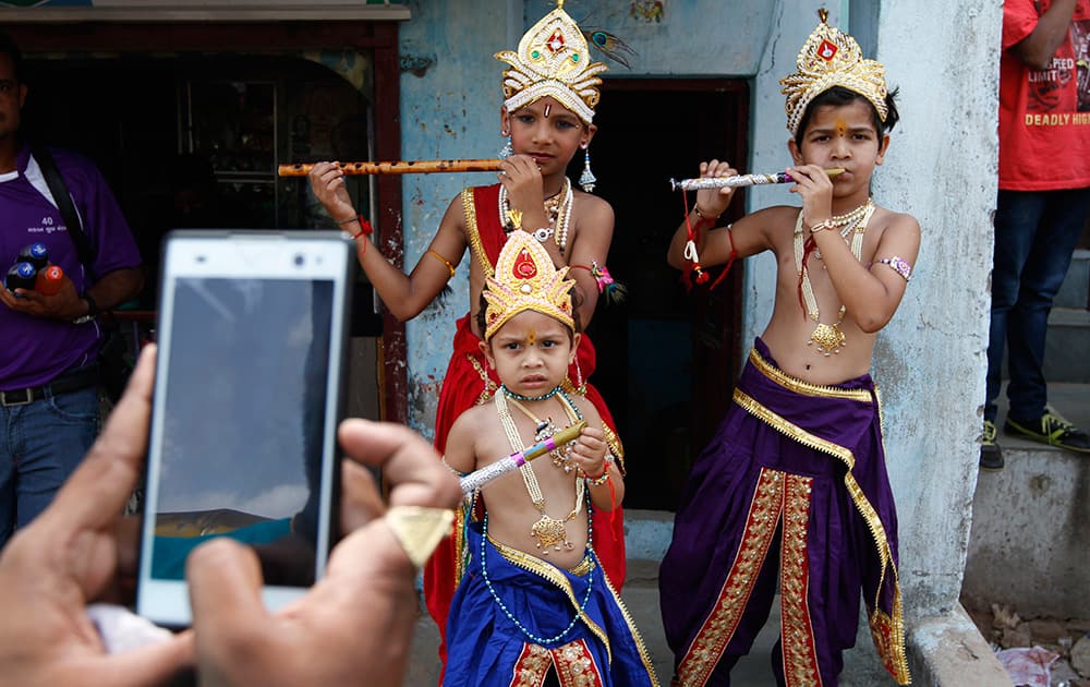 An Indian man takes pictures of children dressed as Hindu god Krishna during Janmashtami festival celebrations in Ahmadabad.