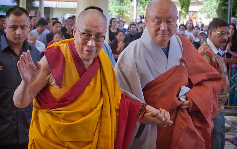 Tibetan spiritual leader the Dalai Lama greets devotees as he arrives to give a talk at the Tsuglakhang temple in Dharmsala.