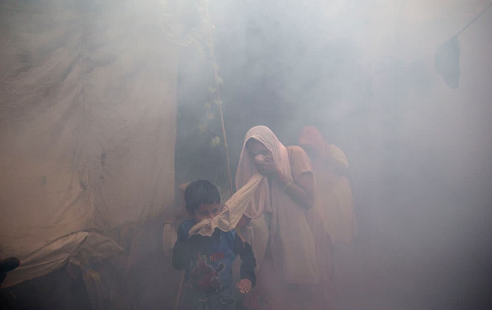 Residents cover their face and run in smoke as a municipal worker fumigates a residential area to prevent mosquitoes from breeding in New Delhi, India.