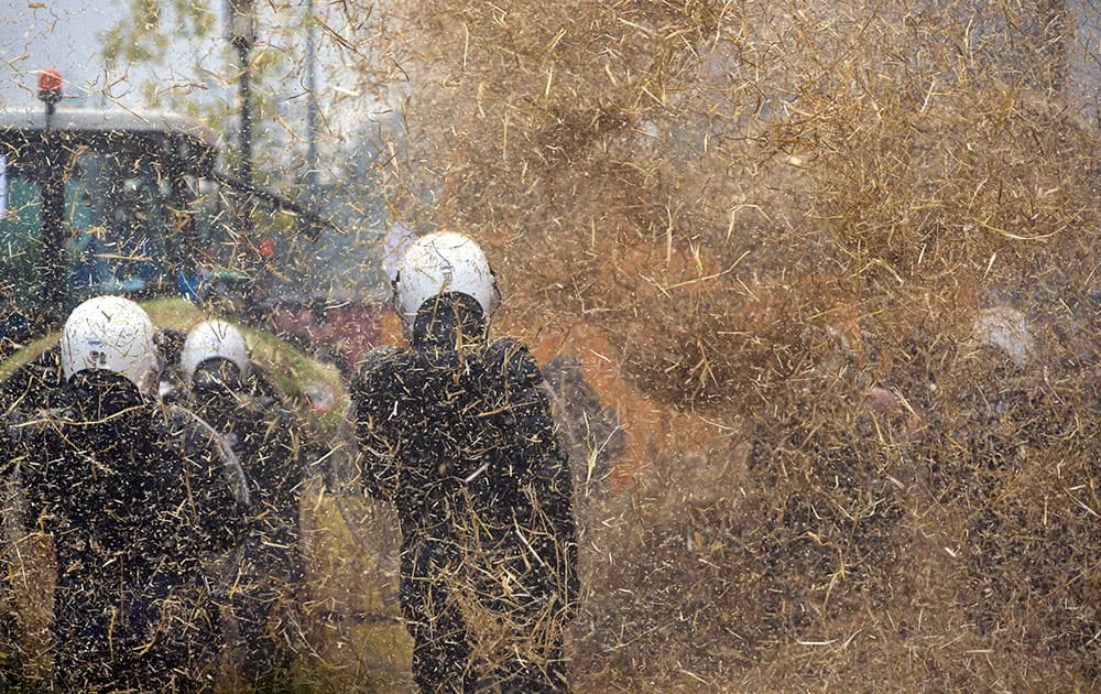 Police are sprayed with a hay machine during a farmers demonstration in Brussels.