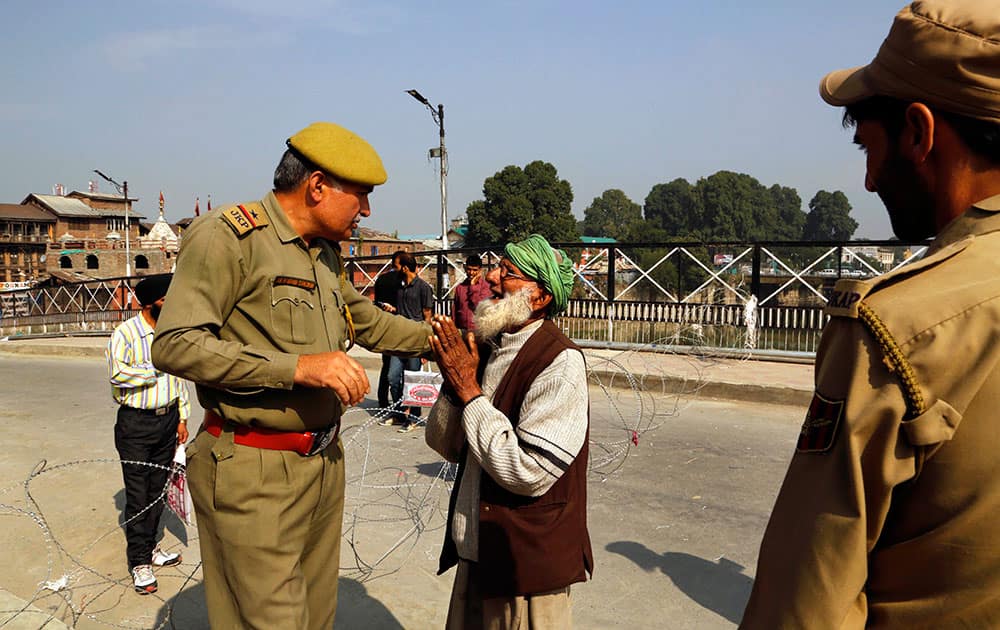 An elderly Kashmiri Muslim pleads to a police officer to cross over a barricade during a general strike on the first anniversary of the devastating floods that killed hundreds, in Srinagar, India.