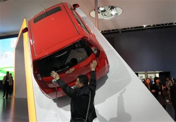 A visitor poses near a Chevrolet Sail car model on display at the China Auto Show