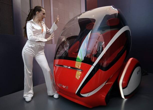 A model poses next to a GM EN-V, or 