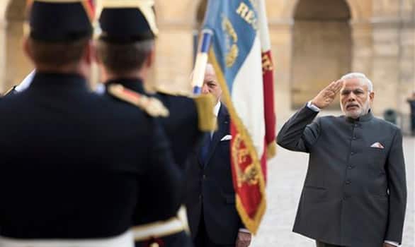 French foreign minister Laurent Fabius, partly hidden at left, and Prime Minister Narendra Modi salute the French flag during a welcoming ceremony in the courtyard of the Hotel des Invalides in Paris.