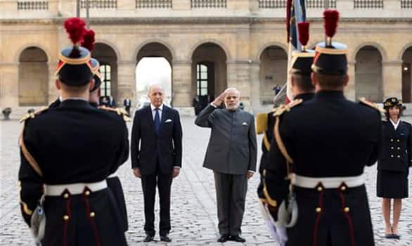 Prime Minister Narendra Modi accompanied by French Foreign Minister Laurent Fabius, salutes during a welcoming ceremony in the courtyard of the Hotel des Invalides in Paris, France.