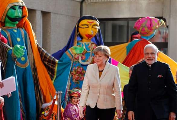 German Chancellor Angela Merkel, left welcomes India's Prime Minister Narendra Modi, right, as a traditional Indian music group performs at the opening of the industrial fair in Hanover, Germany, Sunday, April 12, 2015.