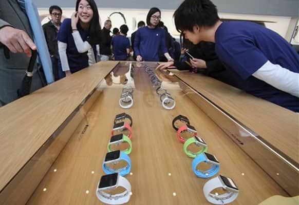 Customers and staff look at models of Apple Watch displayed in a glass case at an Apple Store in Tokyo as Apple Watch made its debut Friday, April 10, 2015. Customers were invited to try them on in stores and order them online.