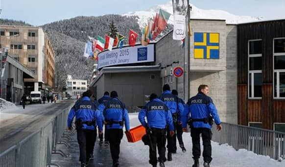 Swiss police officers walk past the Congress Hall in Davos, Switzerland, Monday, Jan. 19, 2015.