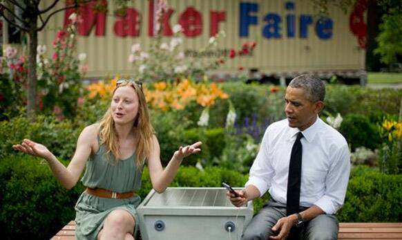 Barack Obama holds up cell phone that is plugged into a 