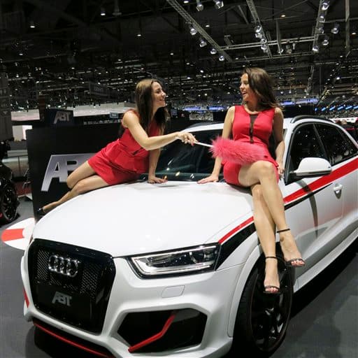 Two hostesses joke with a feather duster as they sit on the hood of an Audi ABT car during the media day of the 2014 Geneva Motor Show, Tuesday, March 4, 2014. The car fair opens its doors to the public March 6 through 16, 2014.