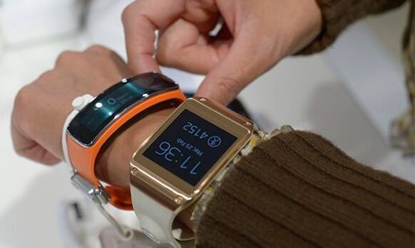 A woman wears the new Samsung Gear 2, right, and at the Samsung Gear Fit , left, at the Mobile World Congress, the world's largest mobile phone trade show in Barcelona, Spain, Tuesday, Feb. 25, 2014.