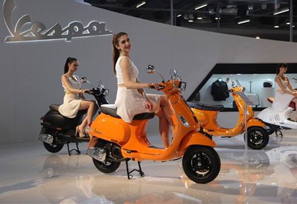 A model poses with a Vespa displayed at the 12th Indian auto Expo in Noida, India, Thursday, Feb. 6, 2014.