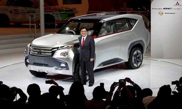 Osamu Masuko, President of Mistubishi Motor Corp. poses with a Mitsubishi Concept GC-PHEV on display at the media preview for the Tokyo Motor Show.