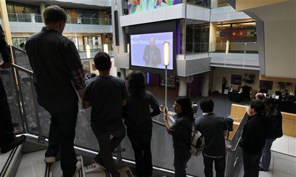 Employees look on as Microsoft CEO Steve Ballmer speaks via a webcast during an event unveiling a new Microsoft Windows operating system.