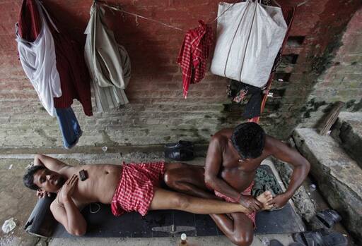 Oily task: A man lies on a mat as a traditional masseuse massages him under a bridge on the banks of the Ganges river in Kolkata. People from all walks of life can enjoy a traditional open-air oil massage for just a few hundred rupees.