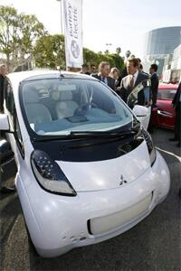 California Governor Arnold Schwarzenegger (R) inspects a Mitsubishi iMiev electric car in LA.