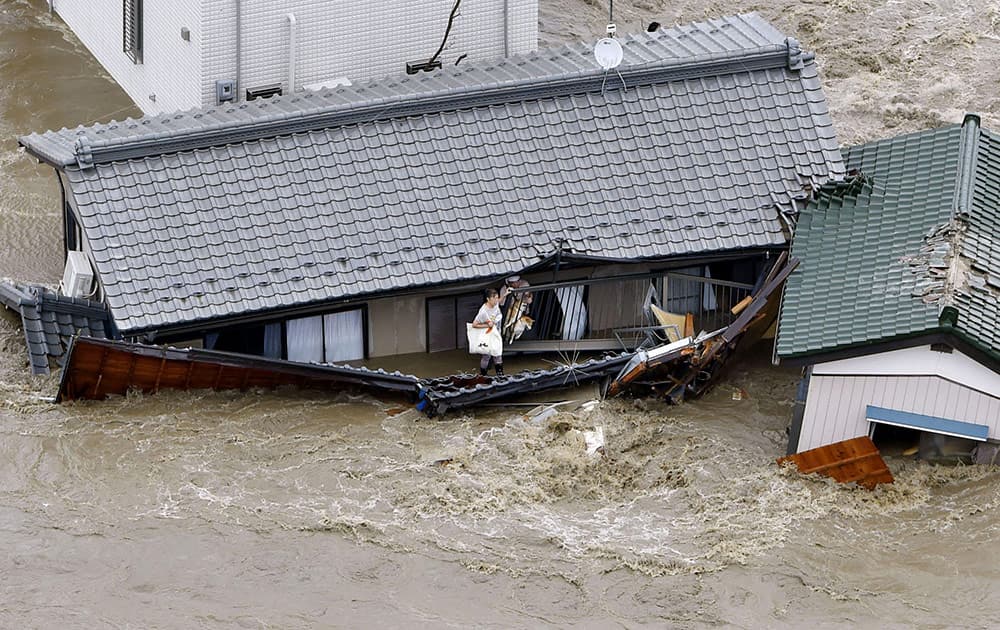 Residents and dogs wait for rescuers as the house is submerged in water flooded from a river in Joso, Ibaraki prefecture, northeast of Tokyo.