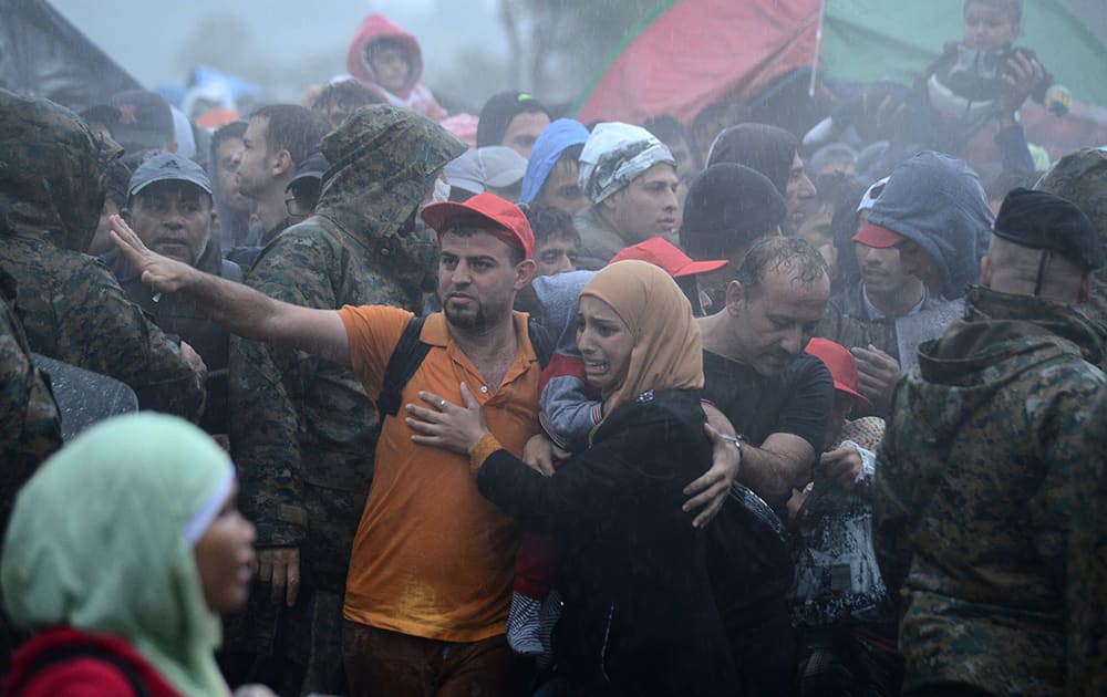 A woman cries as she waits with other refugees and migrants in heavy rainfall to pass from the northern Greek village of Idomeni to southern Macedonia.