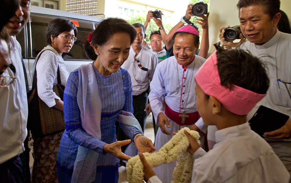 Myanmar's opposition leader Aung San Suu Kyi, center left, receives a flower garland as she visits to meet Catholic religious leaders in Loikaw, Eastern Kayah State.