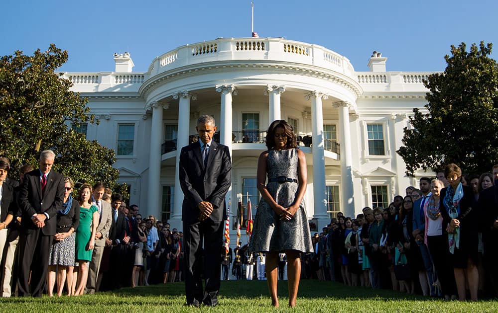 President Barack Obama, first lady Michelle Obama, and others, pause on the South Lawn of the White House in Washington as they observe a moment of silence to mark the 14th anniversary of the 9/11 attacks.