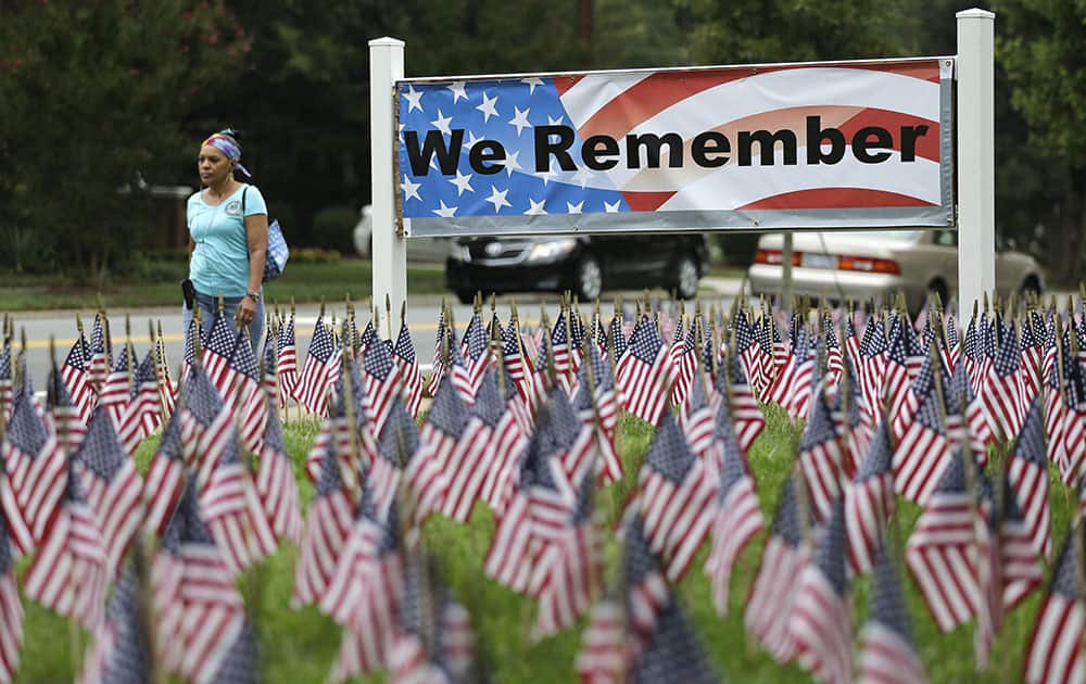 A woman walks past thousands of flags placed to honor of the victims of the 9/11 terrorist attacks in front of Hankins & Whittington Funeral Home in Charlotte, N.C.