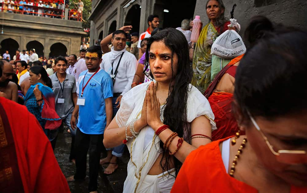 An Indian woman prays after taking a holy dip on the second 