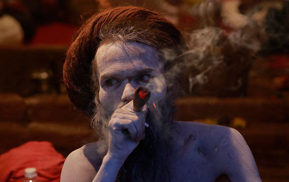 A naked Hindu holy man smokes in a tent during Kumbh Mela, or Pitcher Festival, at Trimbakeshwar in Nasik, India.