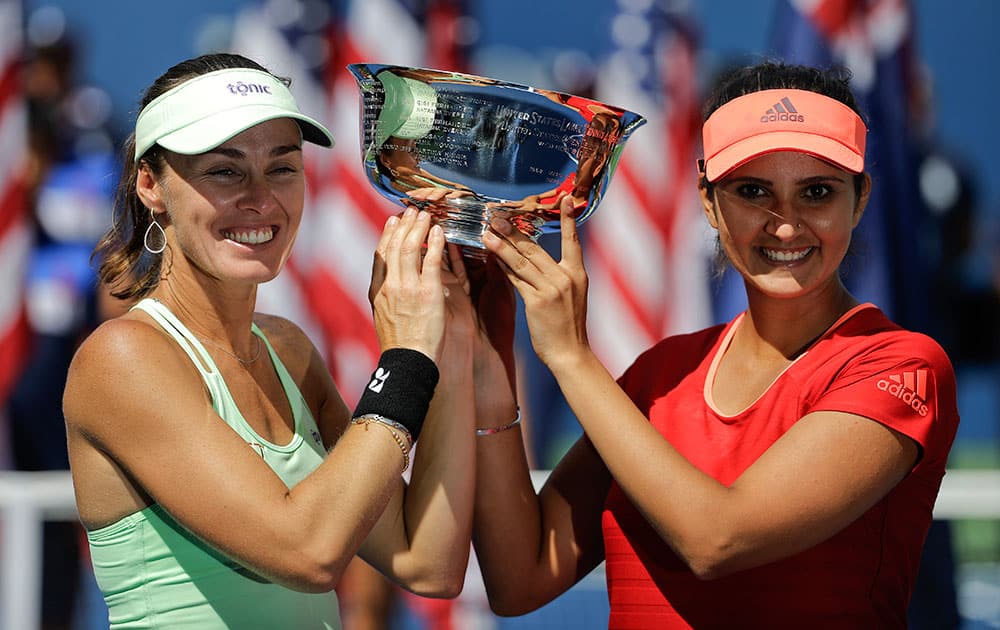 Martina Hingis, of Switzerland, left, and Sania Mirza, of India, hold up the championship trophy after defeating Casey Dellacqua, of Australia, and Yaroslava Shvedova, of Kazakhstan, in the women's doubles championship match of the U.S. Open tennis tournament.