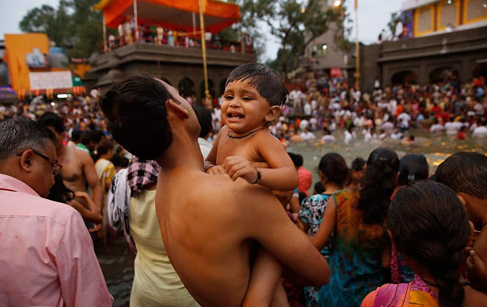 A father carries his son for a holy dip on the second 'shahi snaan' or royal bath in the river Godavari during the ongoing Kumbh Mela or Pitcher Festival, in Nasik, India.